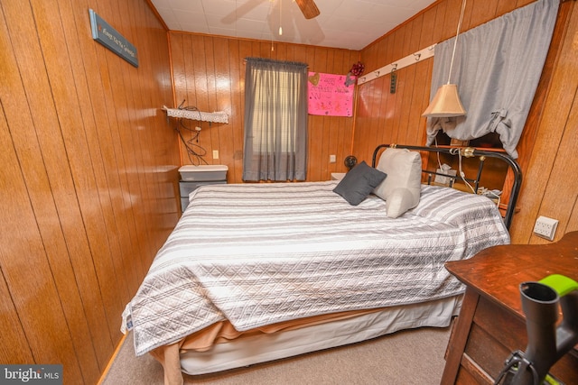 bedroom featuring carpet flooring, a ceiling fan, and wood walls