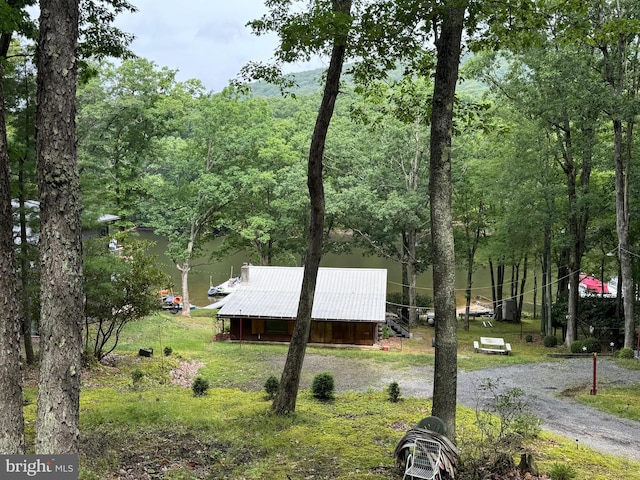 exterior space with a view of trees, an outbuilding, gravel driveway, and an outdoor structure