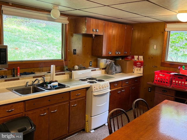 kitchen featuring a drop ceiling, wood walls, light countertops, white electric stove, and a sink