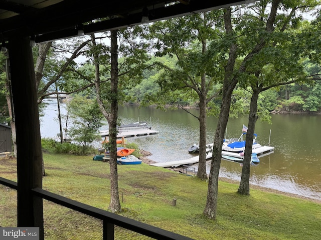 view of dock with a lawn and a water view