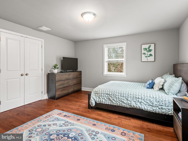 bedroom with visible vents, wood finished floors, a closet, and baseboards