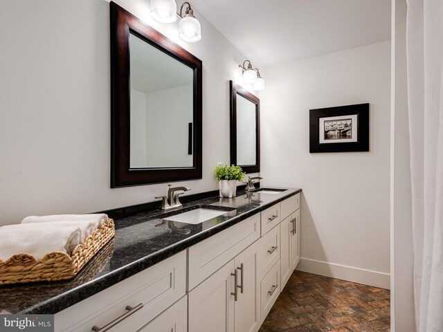 bathroom featuring double vanity, brick floor, baseboards, and a sink