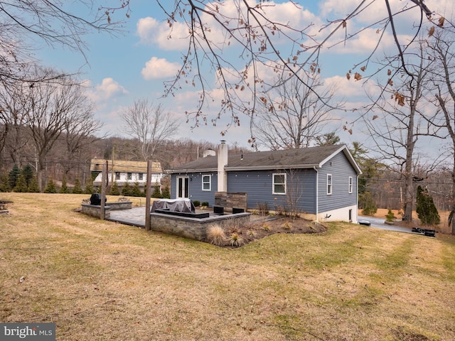 rear view of property with a yard, a patio area, and a chimney