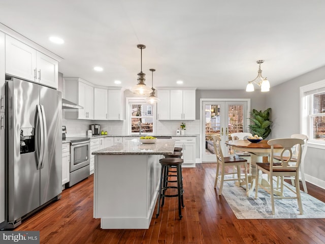 kitchen with dark wood finished floors, white cabinets, backsplash, and appliances with stainless steel finishes