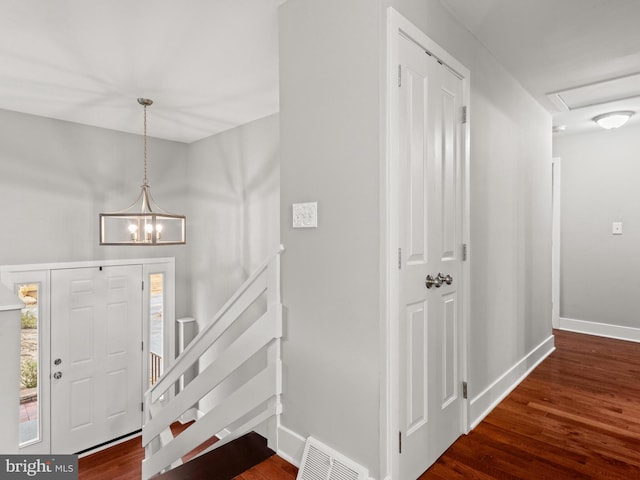 foyer featuring visible vents, baseboards, wood finished floors, and stairs