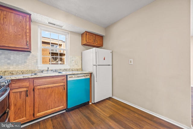 kitchen featuring visible vents, backsplash, dishwasher, freestanding refrigerator, and a sink