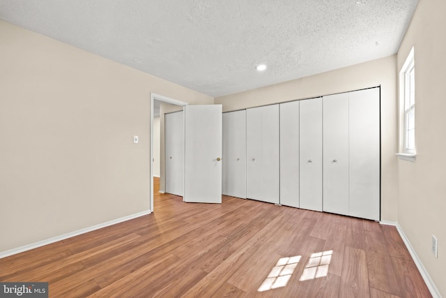 unfurnished bedroom featuring baseboards, a textured ceiling, and wood finished floors