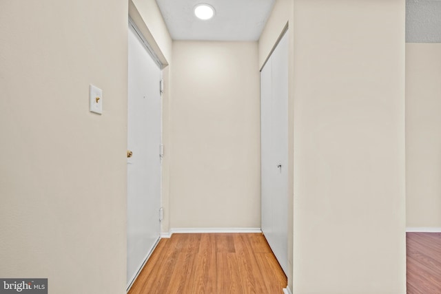 corridor featuring baseboards and light wood-type flooring