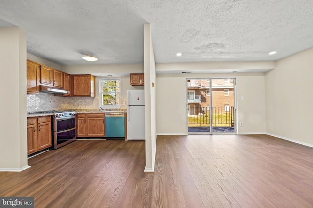 kitchen with tasteful backsplash, under cabinet range hood, dishwasher, range with two ovens, and freestanding refrigerator