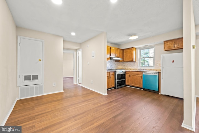 kitchen featuring under cabinet range hood, freestanding refrigerator, light countertops, range with two ovens, and dishwashing machine