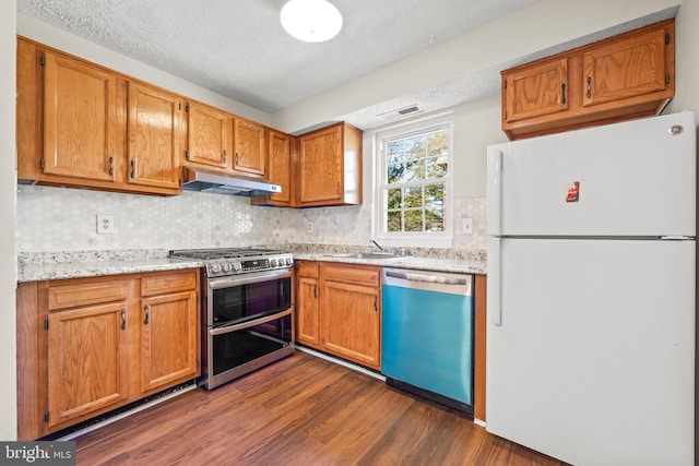 kitchen featuring under cabinet range hood, double oven range, a sink, freestanding refrigerator, and dishwasher