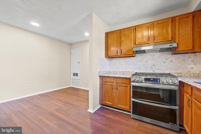 kitchen featuring dark wood-style floors, backsplash, double oven range, and under cabinet range hood