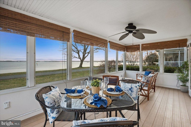 sunroom / solarium with ceiling fan and a water view