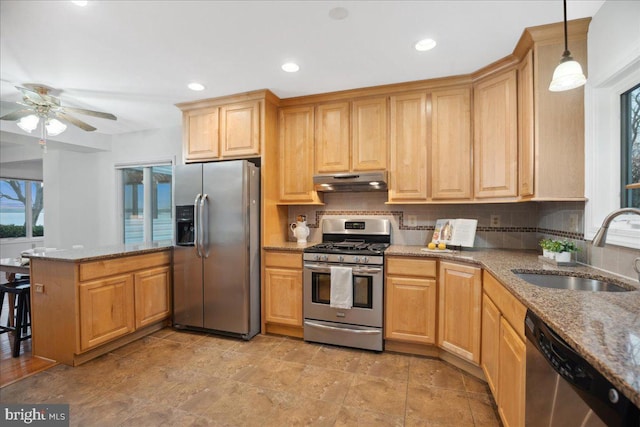 kitchen featuring a peninsula, a sink, under cabinet range hood, appliances with stainless steel finishes, and tasteful backsplash