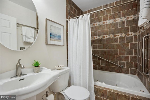 full bathroom with tiled shower / bath combo, toilet, and a sink