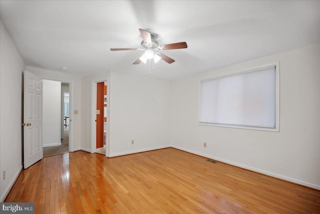 spare room with visible vents, ceiling fan, baseboards, and light wood-style floors