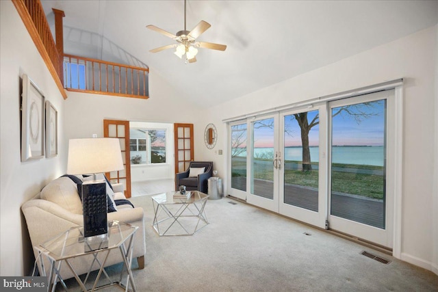 living room with a ceiling fan, visible vents, carpet floors, high vaulted ceiling, and french doors