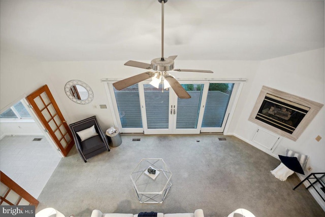 unfurnished living room featuring visible vents, baseboards, carpet, ceiling fan, and a glass covered fireplace