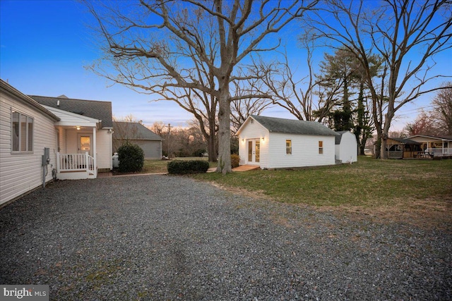 yard at dusk featuring an outbuilding and driveway