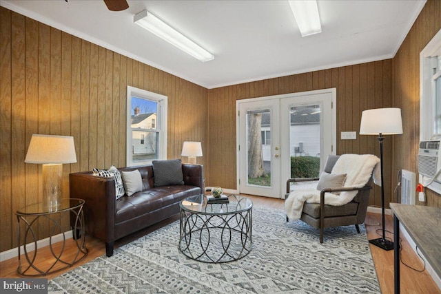 living room with a healthy amount of sunlight, french doors, ornamental molding, and wood finished floors