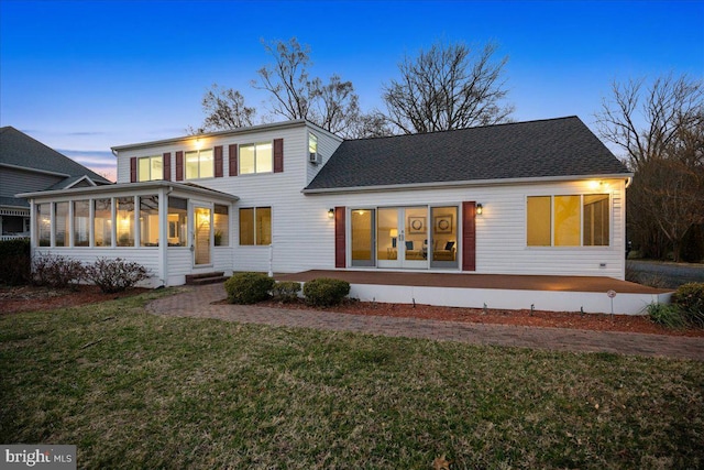 view of front facade featuring a patio area, a front yard, roof with shingles, and a sunroom