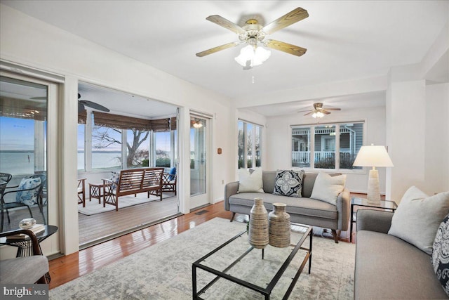 living area with visible vents, wood finished floors, and a ceiling fan