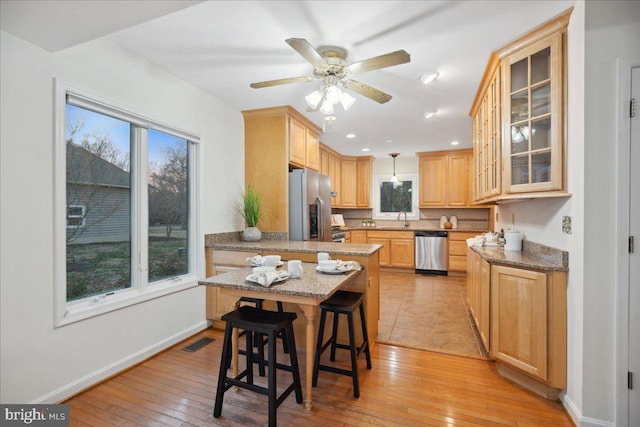 kitchen with a sink, stainless steel appliances, light wood-style floors, and visible vents