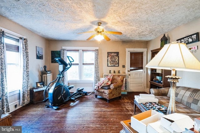 workout room with baseboards, a textured ceiling, ceiling fan, and wood finished floors