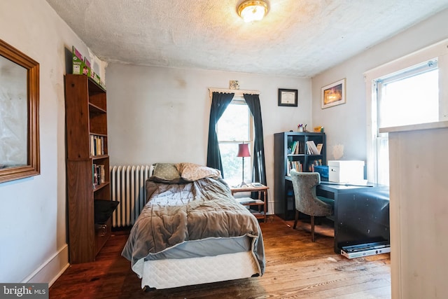 bedroom with hardwood / wood-style flooring, radiator, baseboards, and a textured ceiling