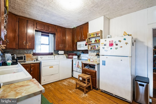 kitchen with light wood finished floors, a toaster, washing machine and dryer, white appliances, and a textured ceiling