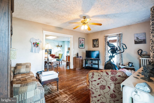 living room with ceiling fan, baseboards, a textured ceiling, and hardwood / wood-style floors