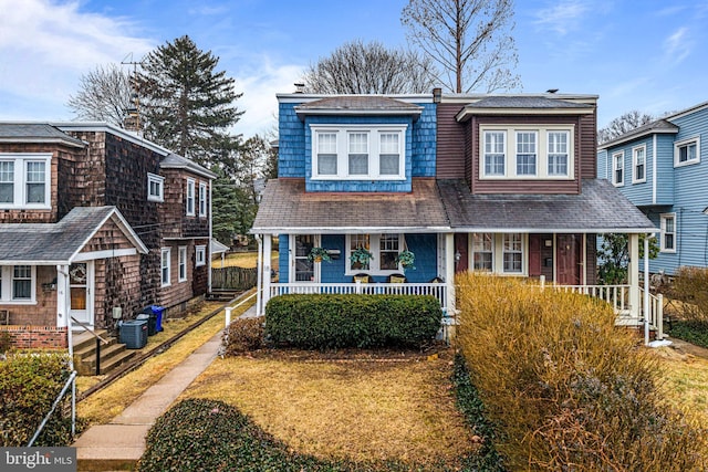 view of front of home with covered porch, central AC, and fence