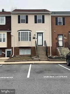 townhome / multi-family property featuring brick siding, uncovered parking, and entry steps