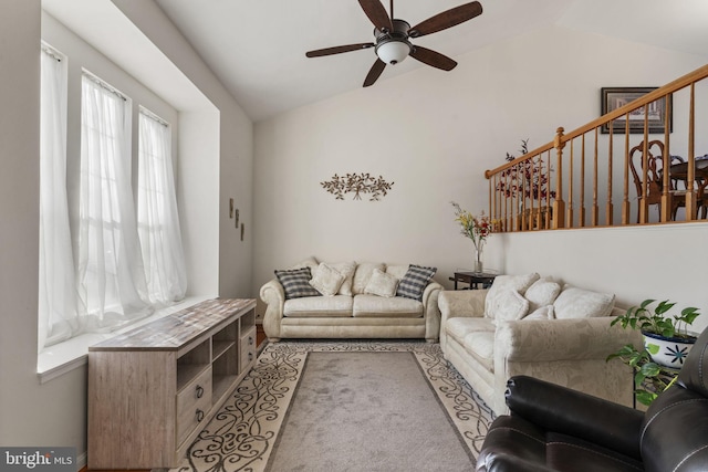 carpeted living room with ceiling fan, stairs, and vaulted ceiling