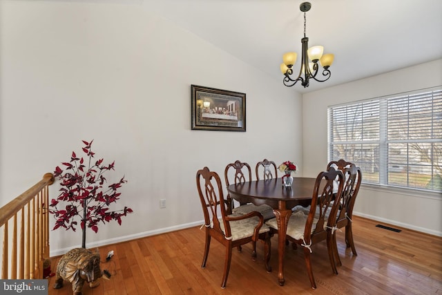 dining area featuring visible vents, light wood-style floors, an inviting chandelier, baseboards, and vaulted ceiling