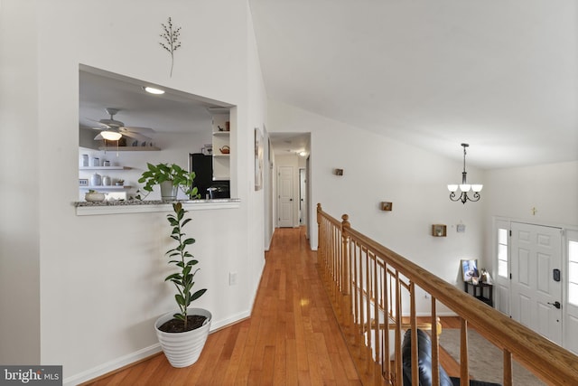 hall featuring an upstairs landing, an inviting chandelier, lofted ceiling, and hardwood / wood-style floors