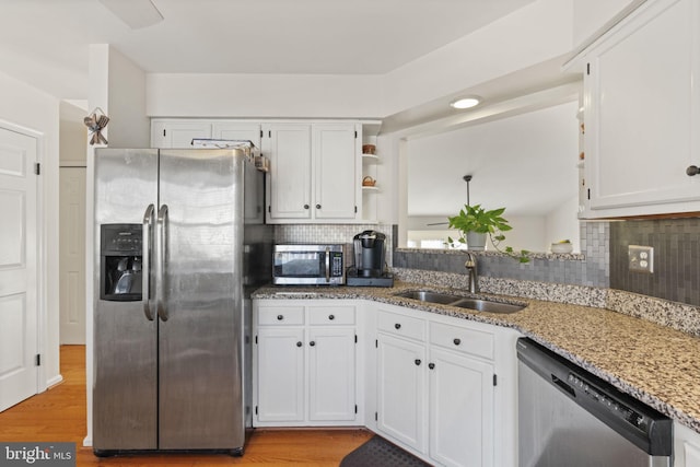 kitchen with white cabinets, light stone counters, appliances with stainless steel finishes, and a sink