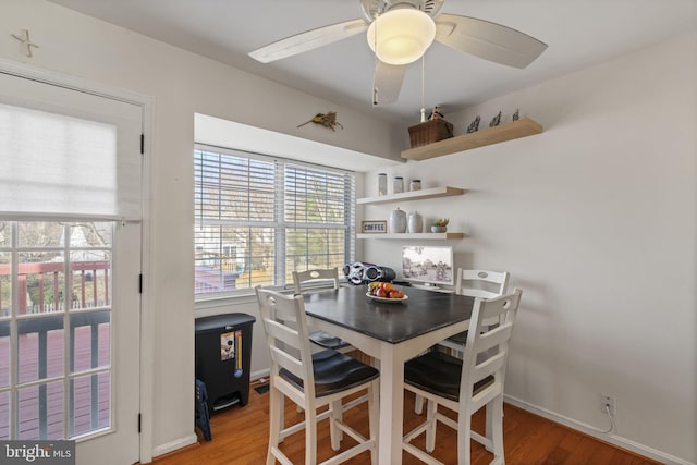 dining room with light wood finished floors, baseboards, and a ceiling fan