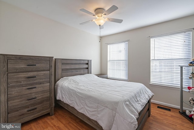 bedroom featuring visible vents, baseboards, wood finished floors, and a ceiling fan