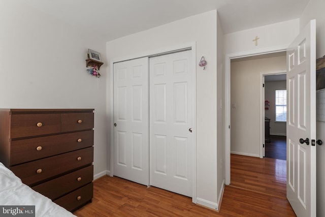 bedroom with a closet, baseboards, and wood finished floors