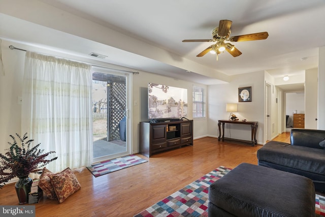 living area featuring visible vents, baseboards, ceiling fan, and wood finished floors