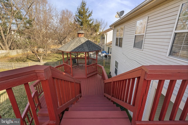 wooden deck featuring a gazebo, stairs, and fence