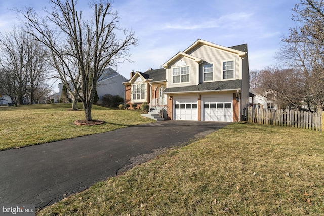 tri-level home with a front yard, fence, a garage, and driveway