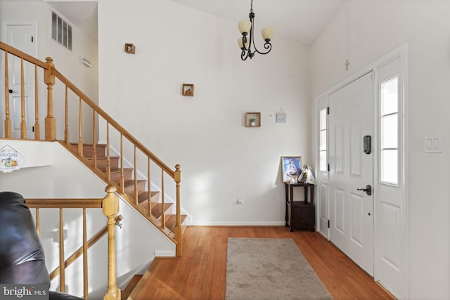 entryway with visible vents, baseboards, stairs, a towering ceiling, and wood finished floors