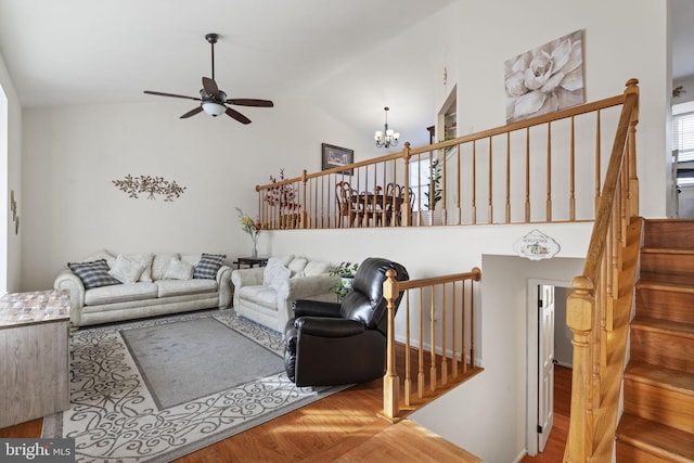 living room with wood finished floors, ceiling fan with notable chandelier, and high vaulted ceiling