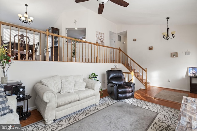 living area with ceiling fan with notable chandelier, stairs, lofted ceiling, and wood finished floors