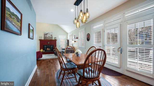 dining space with dark wood finished floors, a healthy amount of sunlight, and a brick fireplace