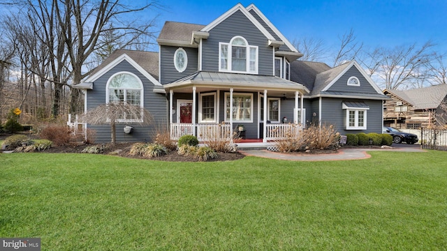 view of front facade featuring a front lawn, covered porch, and a shingled roof