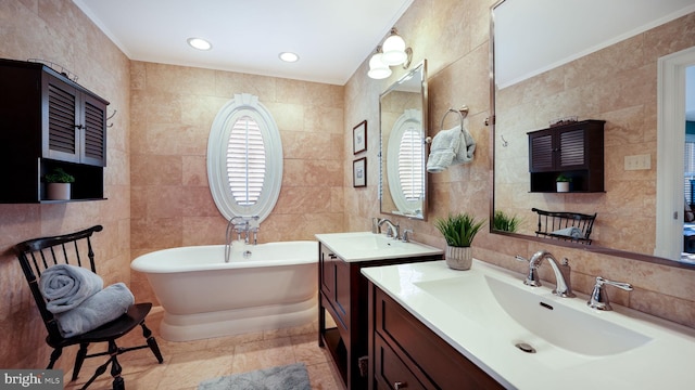 bathroom with a sink, a freestanding tub, two vanities, and tile walls