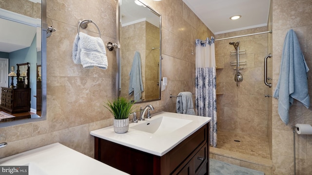 bathroom with tiled shower, tile walls, ornamental molding, and vanity